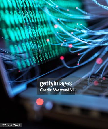 Binary code and fibre optic representing computer virus attack on laptop Binary code and fibre optic representing computer virus attack on laptop