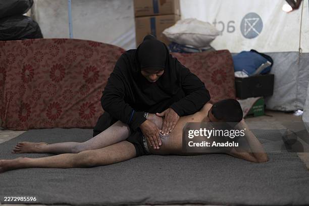 Palestinian woman Wisam Abdulhadi, who lost her husband in an Israeli attack, is seen with her children who have developed skin diseases at where...