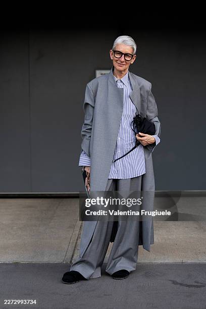 Susanna Cucco wears a light grey longline open blazer over a blue and white pinstripe oversized shirt, with wide-leg light grey tailored trousers and...
