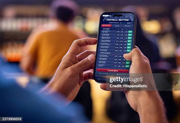 nahaufnahme eines fußballfans, der online über eine mobile app wettet - sportwetten stock-fotos und bilder