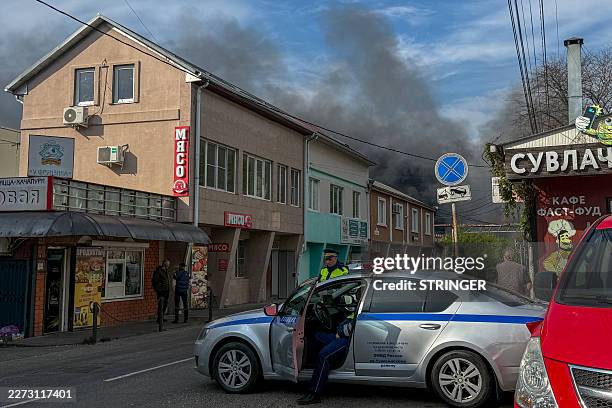 Russian police officers secure an area as smoke rises following a recent drone attack on the Tuapse oil refinery in Tuapse, Krasnodar region on April...