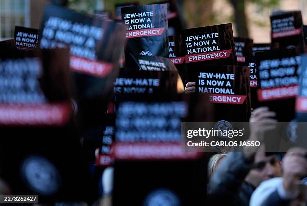 People hold banners reading Jew-Hate is Now a National Emergency as they attend a rally organised by the Campaign Against Antisemitism, opposite...