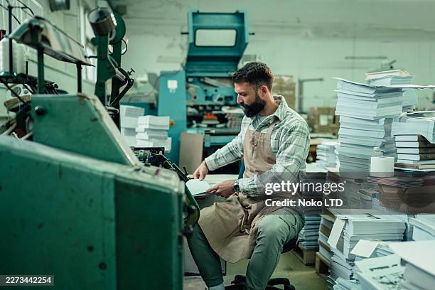 print worker operating industrial machine in production facility, printing documents for publishing house - editor imagens e fotografias de stock