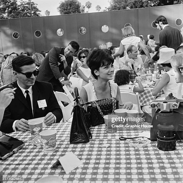 American actress Suzanne Pleshette, wearing a light-coloured sleeveless outfit with a ruffled neckline, sits a table with other guests at a 'Young...