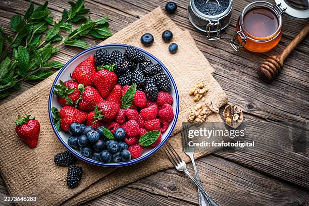 bowl of assorted colorful freshly picked berry fruits on rustic picnic table. organic healthy eating or antioxidant food - blackberry fruit stock pictures, royalty-free photos & images