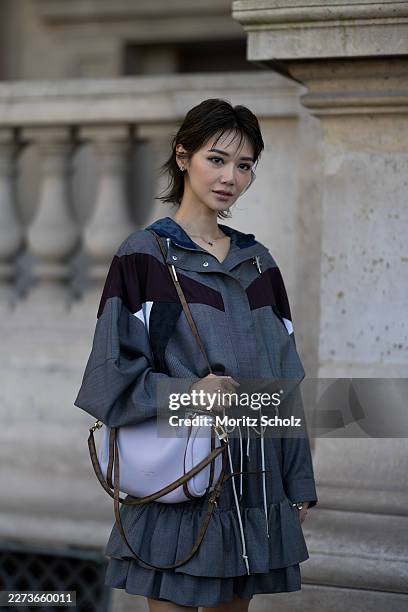 Elva Ni is seen wearing a colour-block windbreaker in dark grey and dark red from Louis Vuitton’s ‘Ready to Wear’ collection; a dark grey pleated...