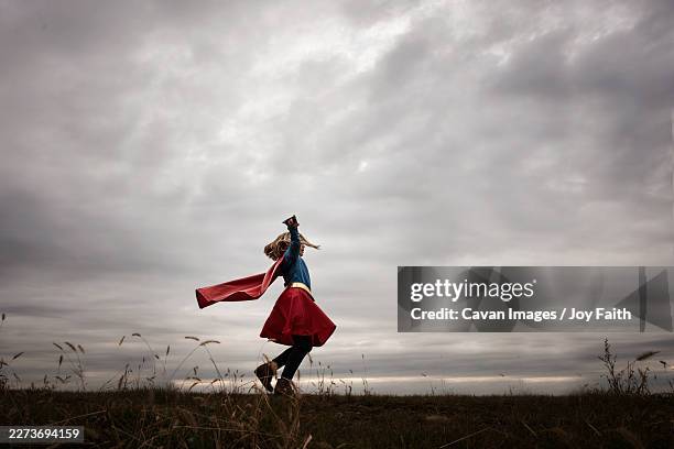 young girl twirling in cape and super hero costume - superhero girl stock pictures, royalty-free photos & images