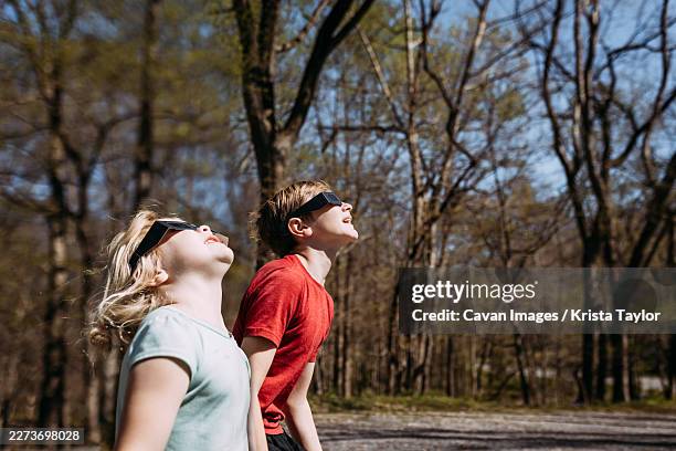children wearing solar eclipse glasses looking up at sun - eclipse imagens e fotografias de stock
