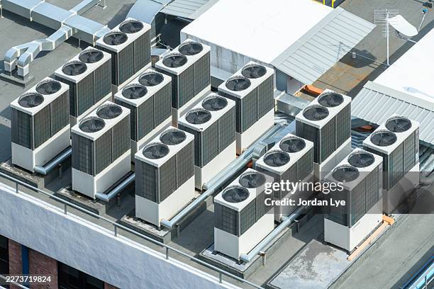 rows of industrial air conditioning compressor units on a commercial building rooftop - kühlturm stock-fotos und bilder