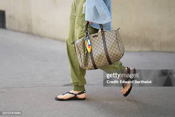 Close-up detail view of green vintage cargo jogger pants, a beige monogram top-handle bag by Gucci, blue and black flat sandals by Miu Miu, during a...
