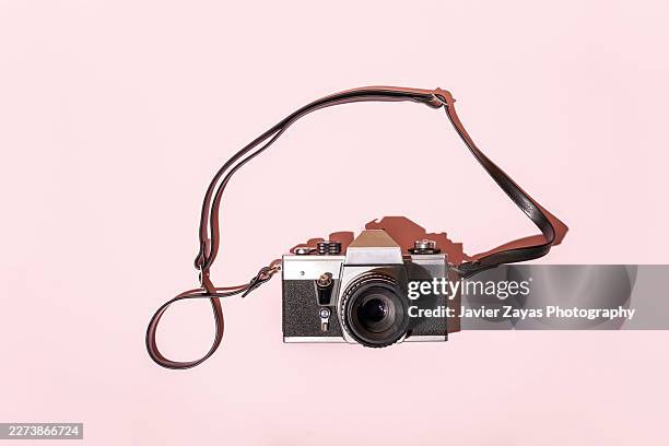 vintage camera with strap on pink background - camera strap stock pictures, royalty-free photos & images