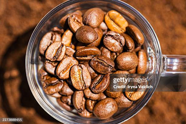 roasted coffee beans in glass cup top view on coffee background. - cafetera exprés fotografías e imágenes de stock