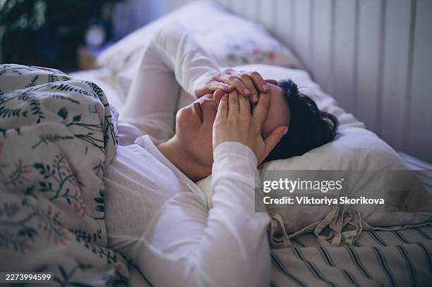 sleepless young woman suffering from insomnia, covering eyes with hands - insomnia stock pictures, royalty-free photos & images