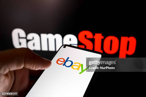 The eBay logo appears on a smartphone screen, and the GameStop logo displays as the background on a laptop computer screen in this photo illustration...