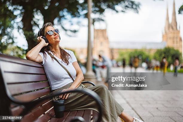 caucasian woman in sydney park enjoying peaceful meditation on bench - park bench stock pictures, royalty-free photos & images