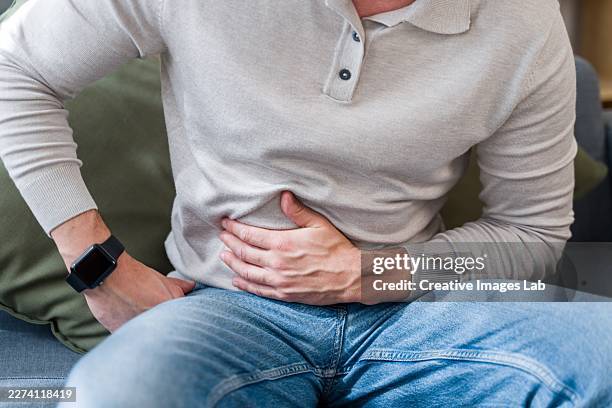 people having stomach pain holding abdomen experiencing discomfort - stomachache stock pictures, royalty-free photos & images