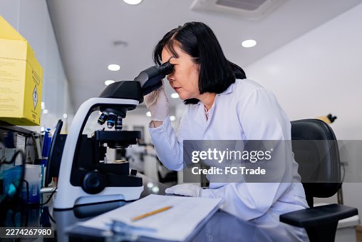 Mature hematologist using microscope in laboratory analyzing samples Mature hematologist using microscope in laboratory analyzing samples