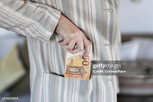 woman putting euro banknotes into coat pocket - money laundering stock pictures, royalty-free photos & images