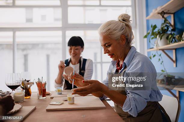two women decorating ceramic pieces they handcrafted in a pottery studio - art and craft stock pictures, royalty-free photos & images