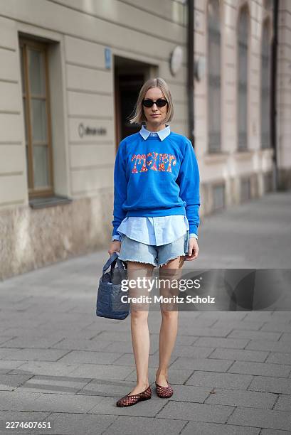Marlies Pia Pfeifhofer is seen wearing a cobalt blue crewneck sweatshirt with a multicolored floral print graphic from Mother; a light blue collared...