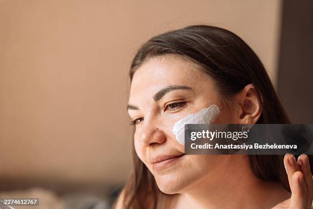 woman with visible sunscreen on cheek, sun protection skincare concept - spreading stock pictures, royalty-free photos & images