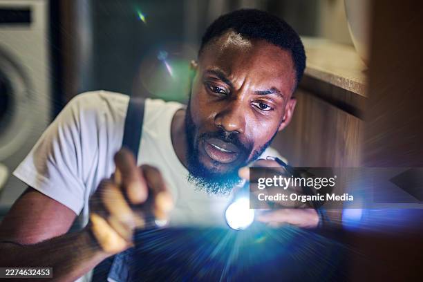 plumber inspecting sink with flashlight in low light - using flashlight stock pictures, royalty-free photos & images