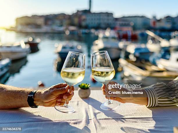 happy couple sitting together in a restaurant by the sea and toasting with wine. - witte wijn stockfoto's en -beelden