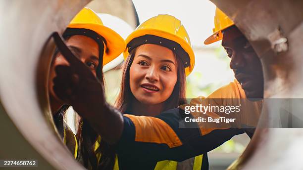 three heavy industry engineers stand in pipe manufacturing factory, use digital tablet computer in industry manufacturing factory. - ethnicity stock pictures, royalty-free photos & images