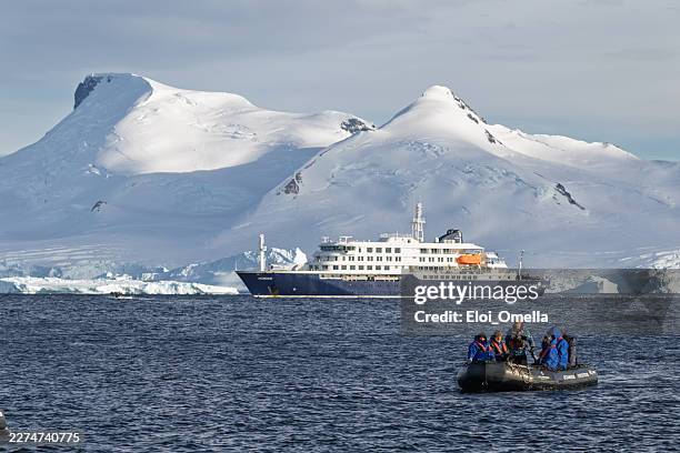 mv hondius cruise ship sailing in antarctica with snow-capped mountains and icebergs, zodiac expedition boat with tourists exploring the icy waters and cold polar environment - epidemic stock pictures, royalty-free photos & images