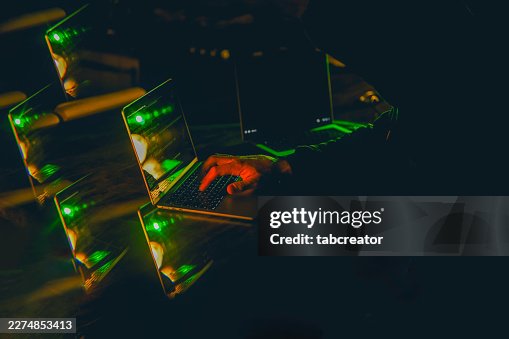 Hacker programming laptop computer in dark creating cyber security breach Hacker programming laptop computer in dark creating cyber security breach