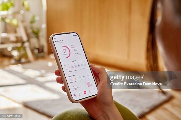 woman tracking menstrual cycle using smartphone application - initiative stock pictures, royalty-free photos & images