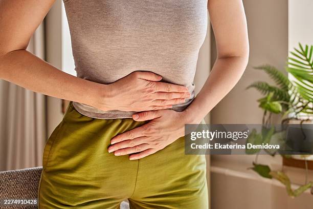 woman experiencing stomach ache and abdominal pain - microorganismo fotografías e imágenes de stock