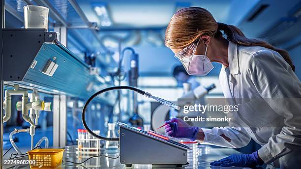 mature adult mature caucasian female professor analyzing sample in laboratory with safety equipment - scientific research stock pictures, royalty-free photos & images