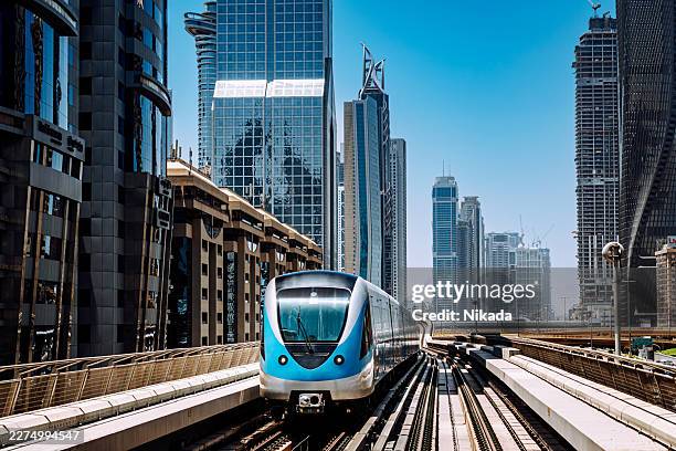 dubai metro train approaching through modern city skyline - commuter train stock pictures, royalty-free photos & images
