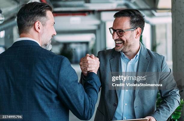 cheerful businessmen clasped hands in the office. - hands clasped stock pictures, royalty-free photos & images