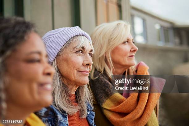 three diverse senior women looking thoughtfully in the same direction at a coastal setting - looking same direction stock pictures, royalty-free photos & images