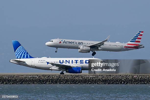 United Airlines plane is taxiing to takeoff as an American Airlines plane lands at San Francisco International Airport in San Francisco, California,...