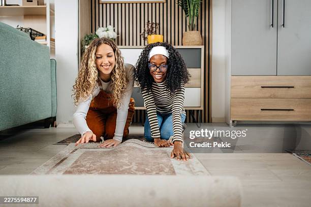 two women unrolling a rug - carpet roll stock pictures, royalty-free photos & images