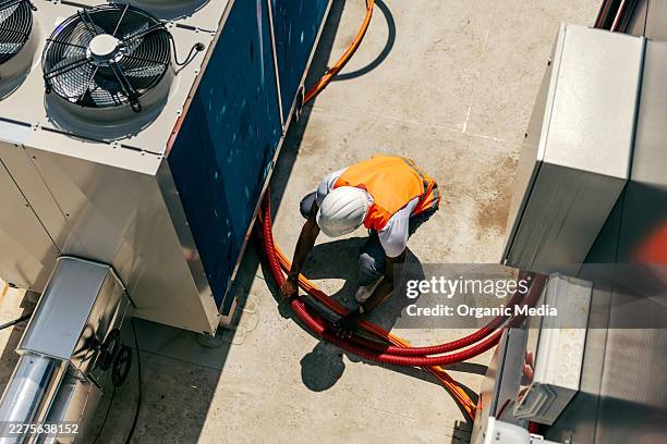hvac technician connecting cables on industrial rooftop unit - rooftop hvac stock pictures, royalty-free photos & images