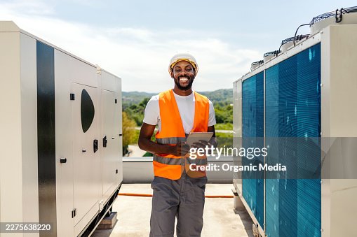Hvac technician smiling while checking system on rooftop Hvac technician smiling while checking system on rooftop