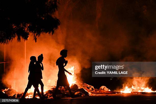 People walk past a fire set by demonstrators during a protest against the lack of energy and blackouts in the Lawton neighborhood in Havana on May...
