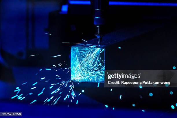 close-up of cnc laser head cutting through metal pipe with intense blue light and glowing sparks, representing advanced manufacturing technology and automation. - laser engraving stock pictures, royalty-free photos & images