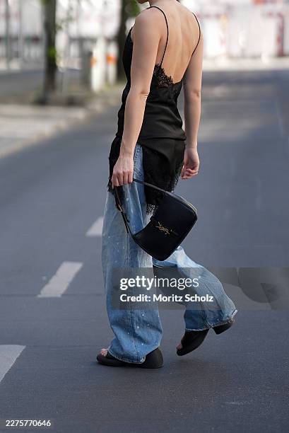 Sophia Geiss is seen wearing a black satin camisole slip top with thin spaghetti straps, a V-neckline with black lace trim, and an asymmetric...