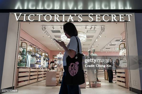Woman Walks Past Victoria's Secret Store While Using Smartphone In Shenzhen Woman Walks Past Victoria's Secret Store While Using Smartphone In Shenzhen