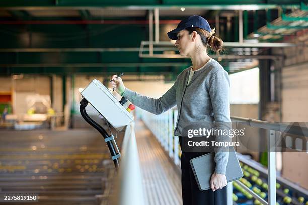 a warehouse engineer operating buttons on a control panel in a futuristic industry setting. - clever storage stock pictures, royalty-free photos & images