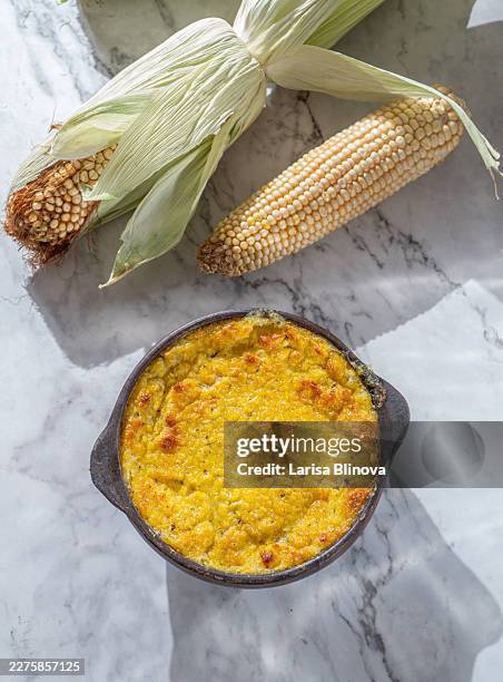 corn casserole in black pottery on marble surface - corn pudding stock pictures, royalty-free photos & images