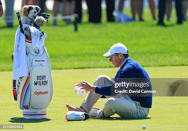 Rory McIlroy of Northern Ireland attends to a blister on his right foot on the third hole during his practice round prior to the PGA Championship at...