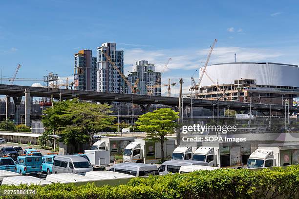 City view with construction sites, cranes, elevated transit infrastructure, high-rise buildings, and a large circular structure under development...