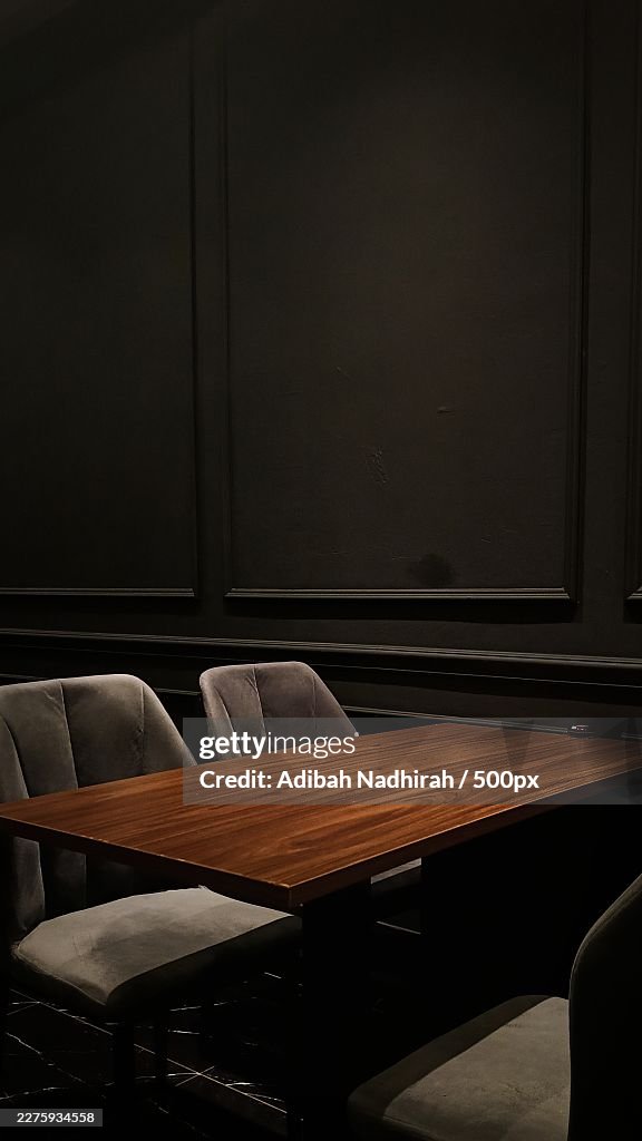 Empty wooden table and chairs in a dimly lit restaurant or bar, creating a moody and intimate atmosphere,Malaysia