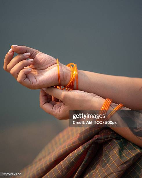 cropped shot of a womans hands adorned with traditional orange bangles, highlighting cultural jewelry and fashion - bangle stock pictures, royalty-free photos & images